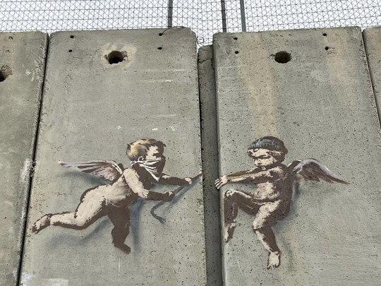 Banksy graffiti of two putti crowbarring a gap in the Palestine wall